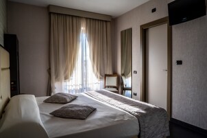 Una habitación de hotel con una cama grande, una silla, un escritorio y un televisor en la pared.