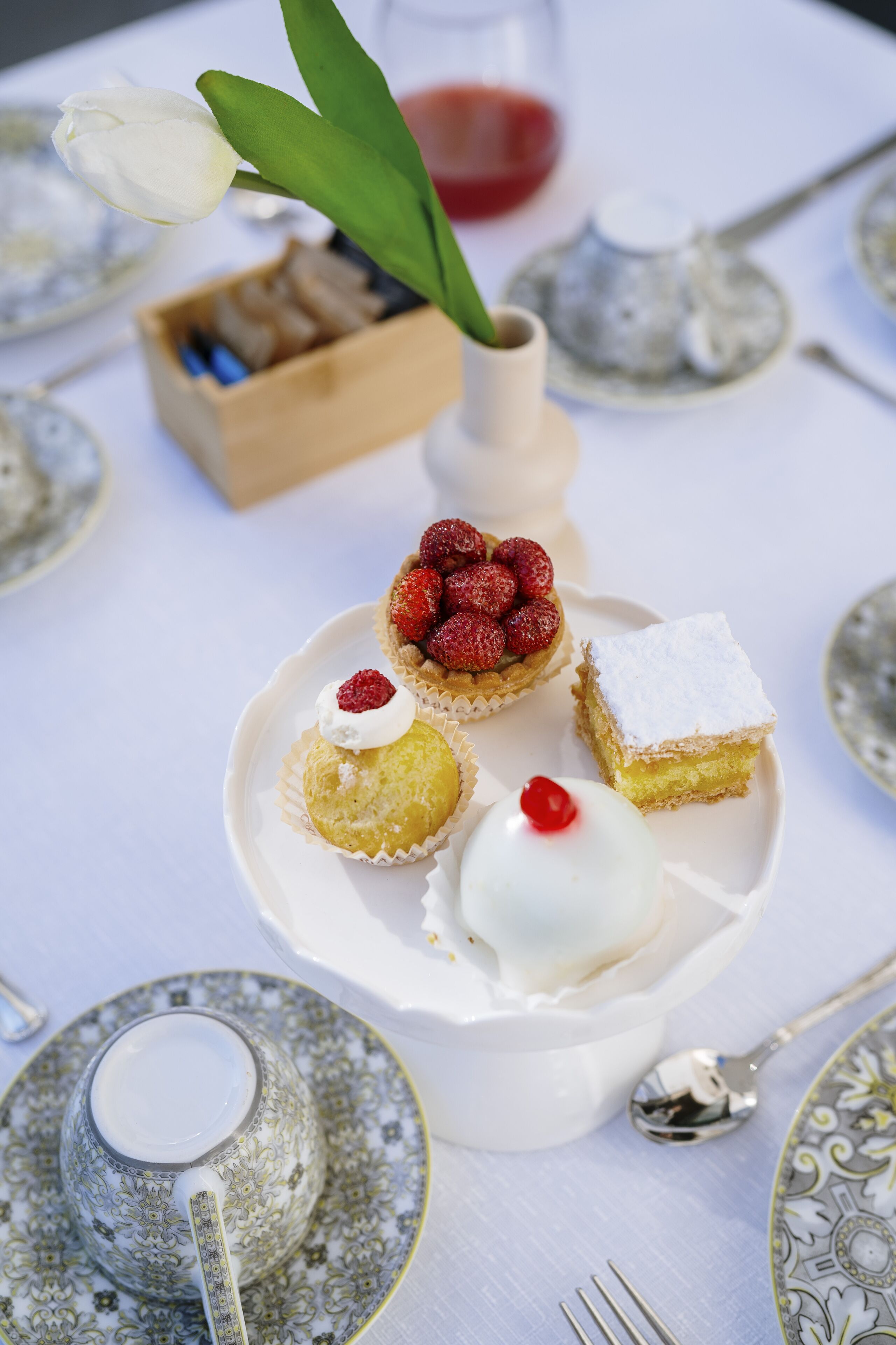 Una mesa dispuesta con vajilla de porcelana, cubiertos y una variedad de postres.