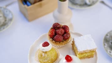 Una mesa dispuesta con vajilla de porcelana, cubiertos y una variedad de postres.