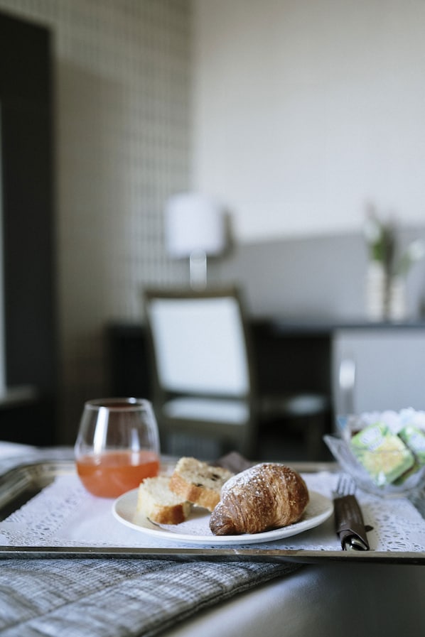 A tray with croissant, toast, and a glass of orange juice on a table in a hotel room.