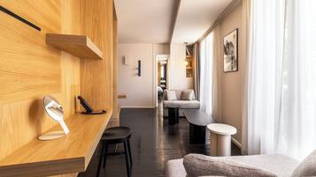 A modern hotel lobby with a wooden reception desk, a mirror, a black telephone, a sofa, and a small table.