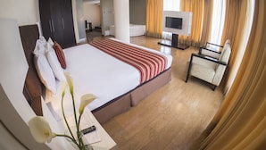 A hotel room with a large bed, a TV, a chair, and a desk with a remote control. - Allpa Hotel & Suites (Lima)