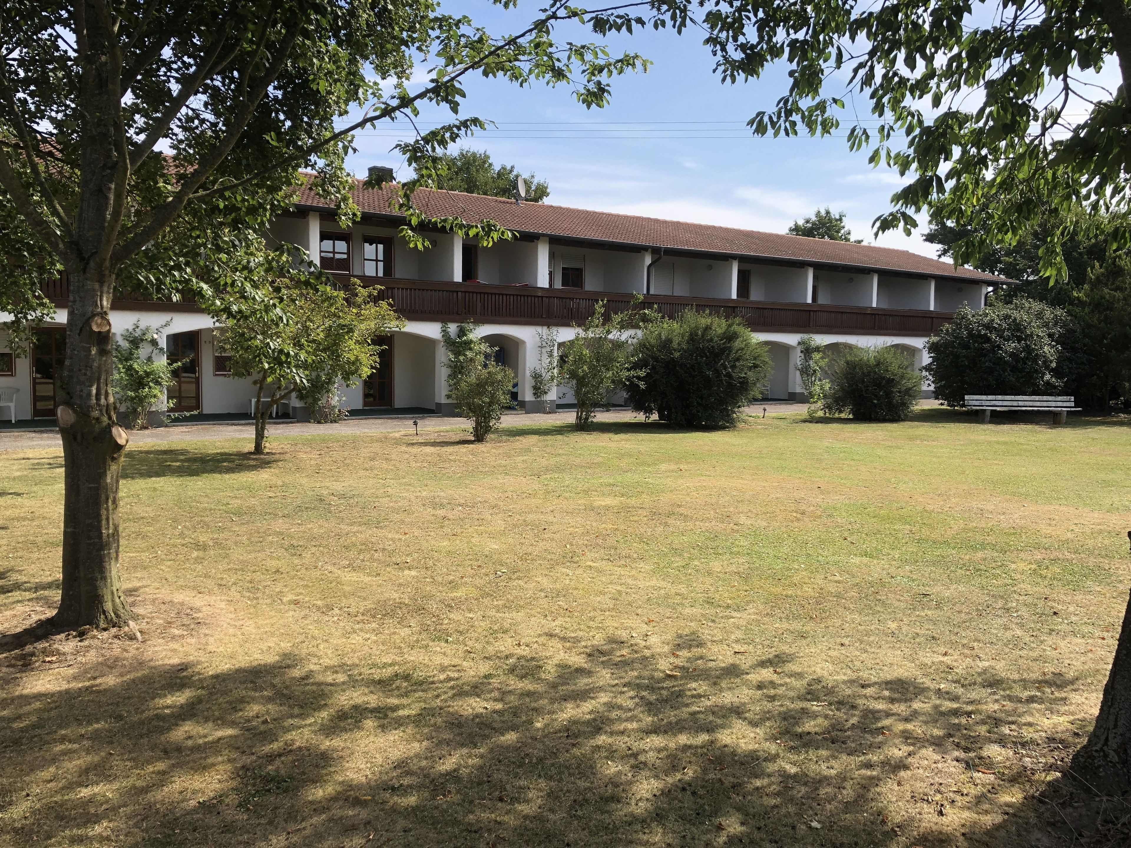 A building with a tiled roof, multiple windows, and a central courtyard with grass and trees.