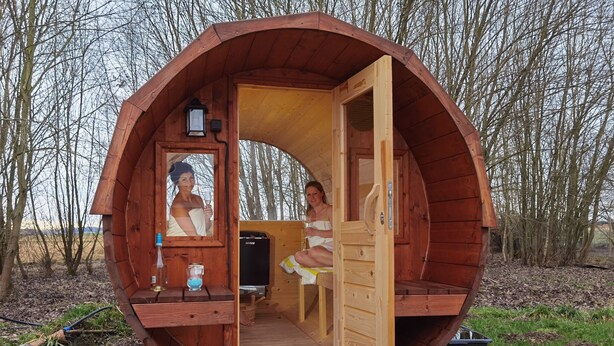A wooden spherical structure with a door open, revealing a person inside. - PAGA Hotel (Aidenbach)