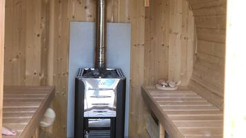 A sauna with a central heating unit, wooden benches, and a wooden interior.