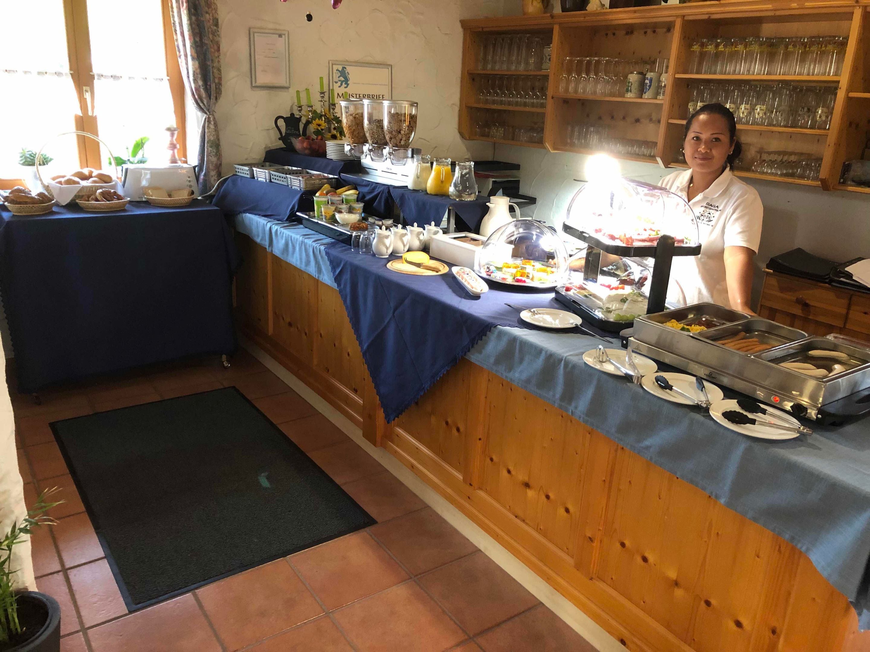 A buffet setup with various food items, a coffee machine, and a person serving.