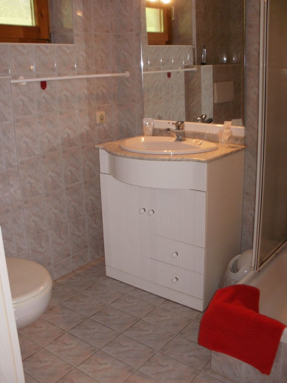 A bathroom with a white sink, mirror, and tiled floor.