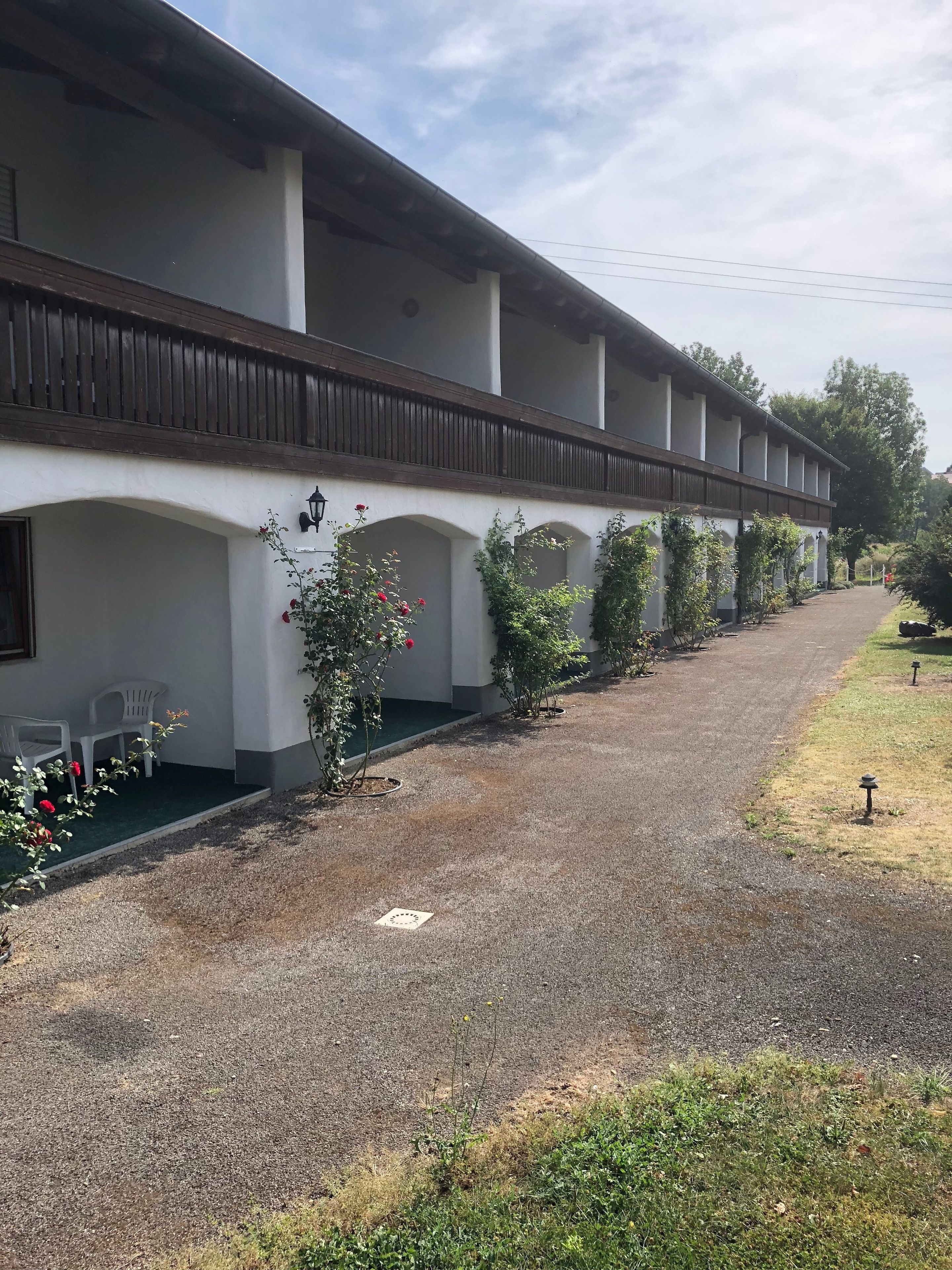 Ein Gebäude mit überdachtem Gang, Außenbereich und Grünflächen.