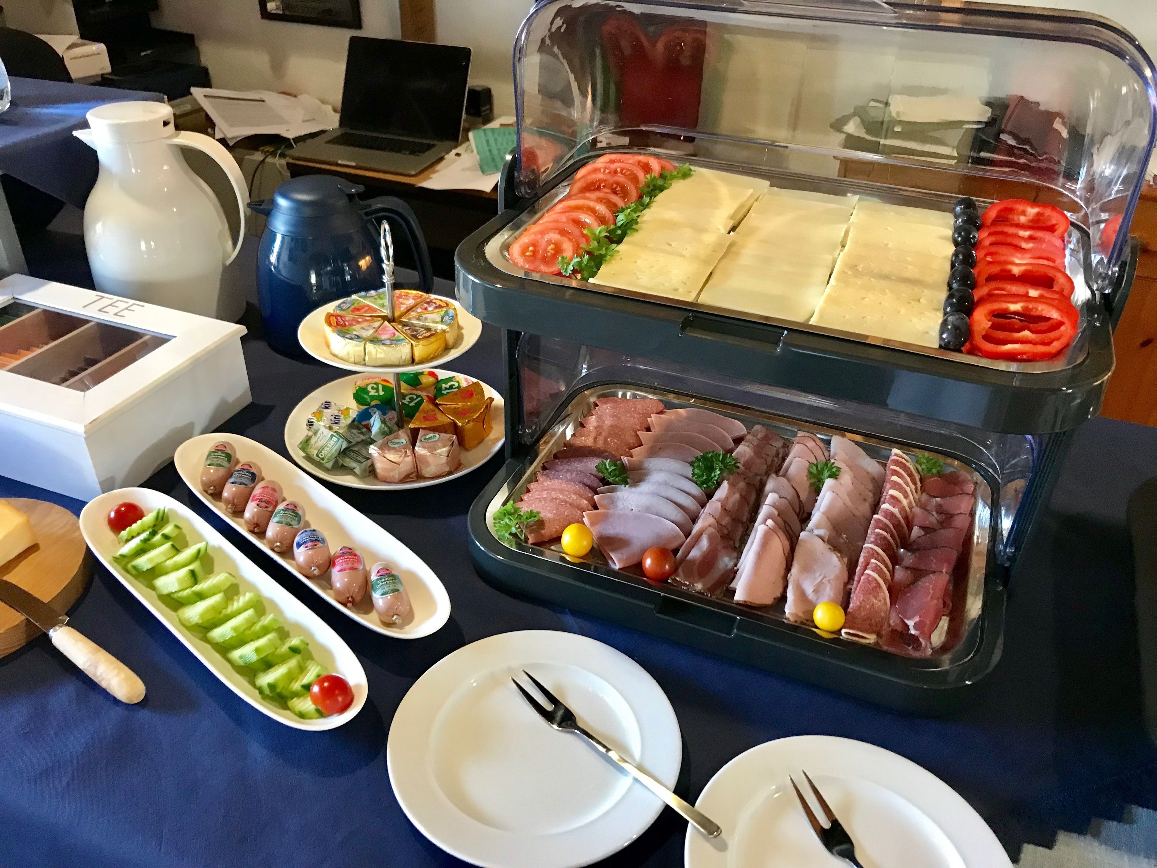 A buffet table with various food items including sliced meats, cheeses, and vegetables.