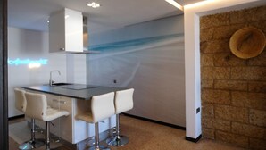 Una cocina moderna con barra, taburetes blancos, un letrero de neón y una pared de ladrillo con un sombrero.