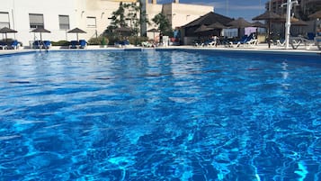 Een seizoensgebonden buitenzwembad, ligstoelen bij het zwembad