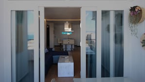 Un interior moderno con un vidrio que da a un espacio de estar con un sofá, una mesita de centro y una mesa de comedor.