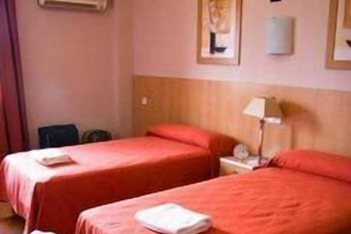 Two single beds with red bedding in a hotel room.