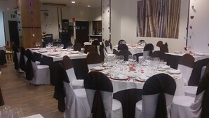 A banquet hall with round tables set for dining, white tablecloths, and black chair covers. - Hotel Las Terrazas (Albolote)