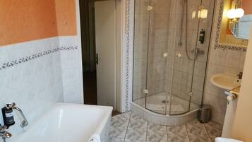 Un baño con ducha de vidrio, bañera y lavamanos.