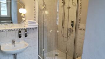 A modern bathroom with a glass-enclosed shower, a sink, and a toilet.