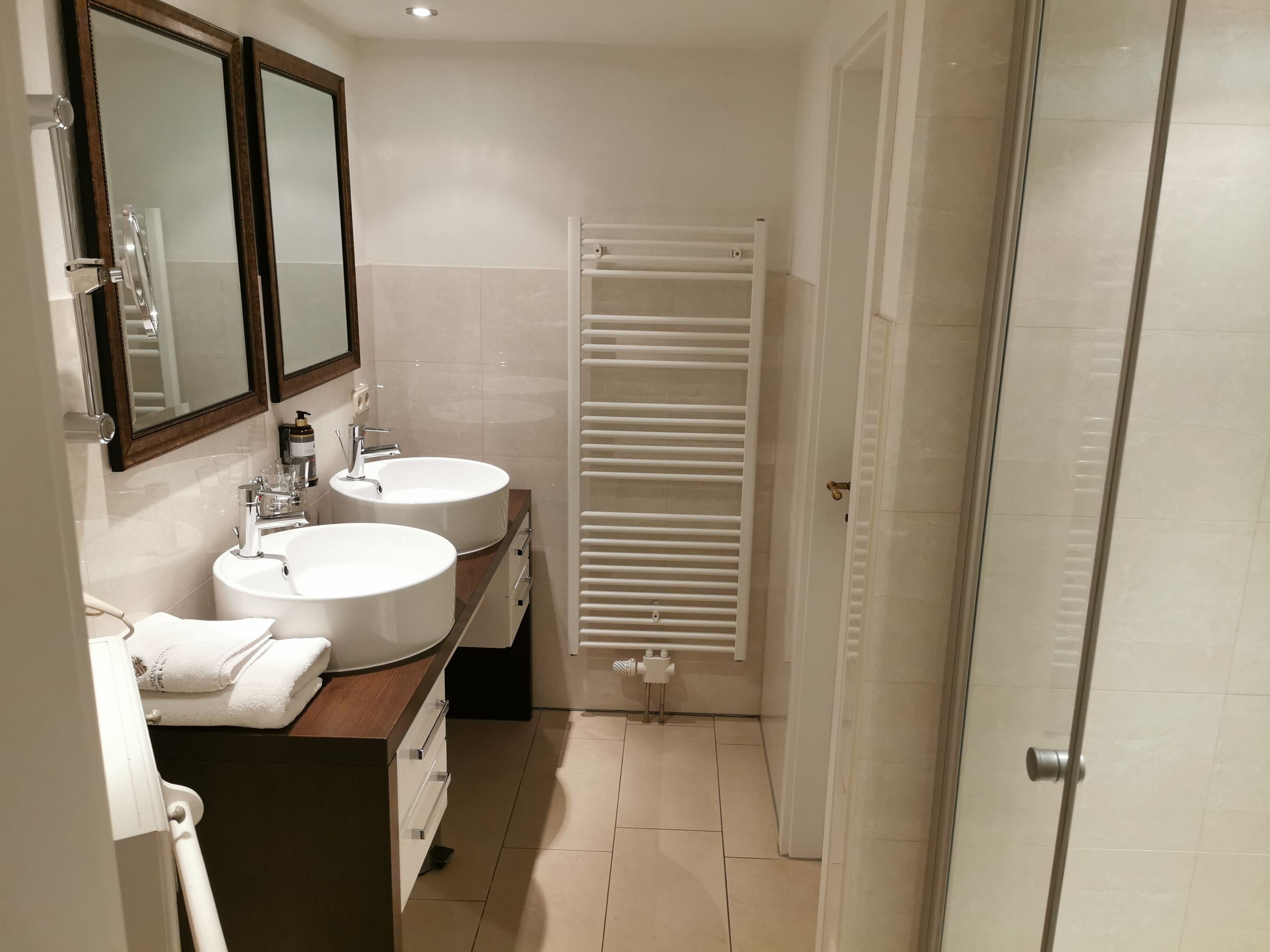 Une salle de bain avec deux lavabos, un miroir et un porte-serviettes.