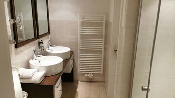 Une salle de bain avec deux lavabos, un miroir et un porte-serviettes.