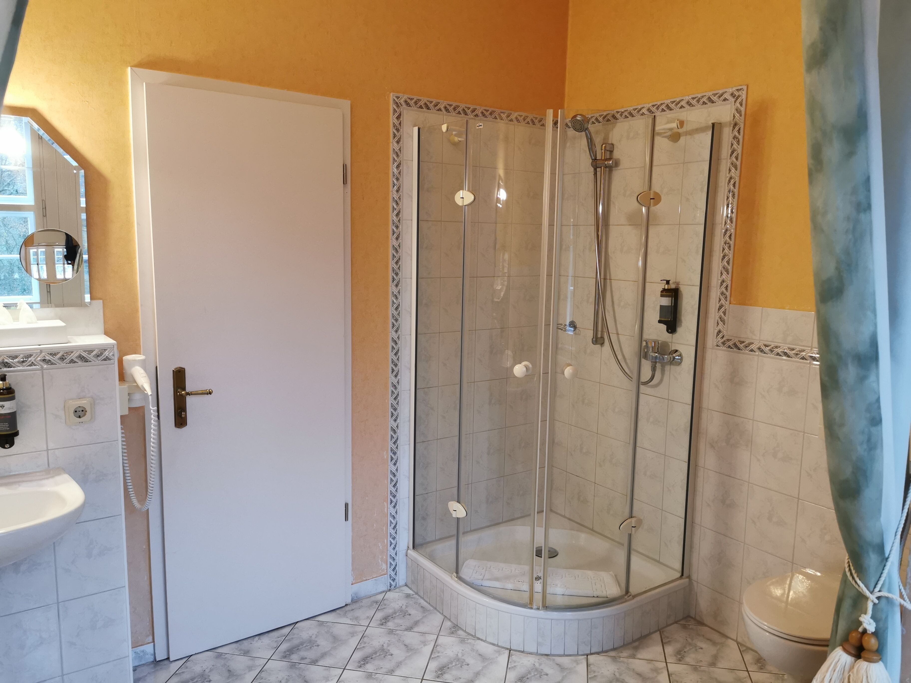 A bathroom with a glass-enclosed shower, a white sink, and a toilet.