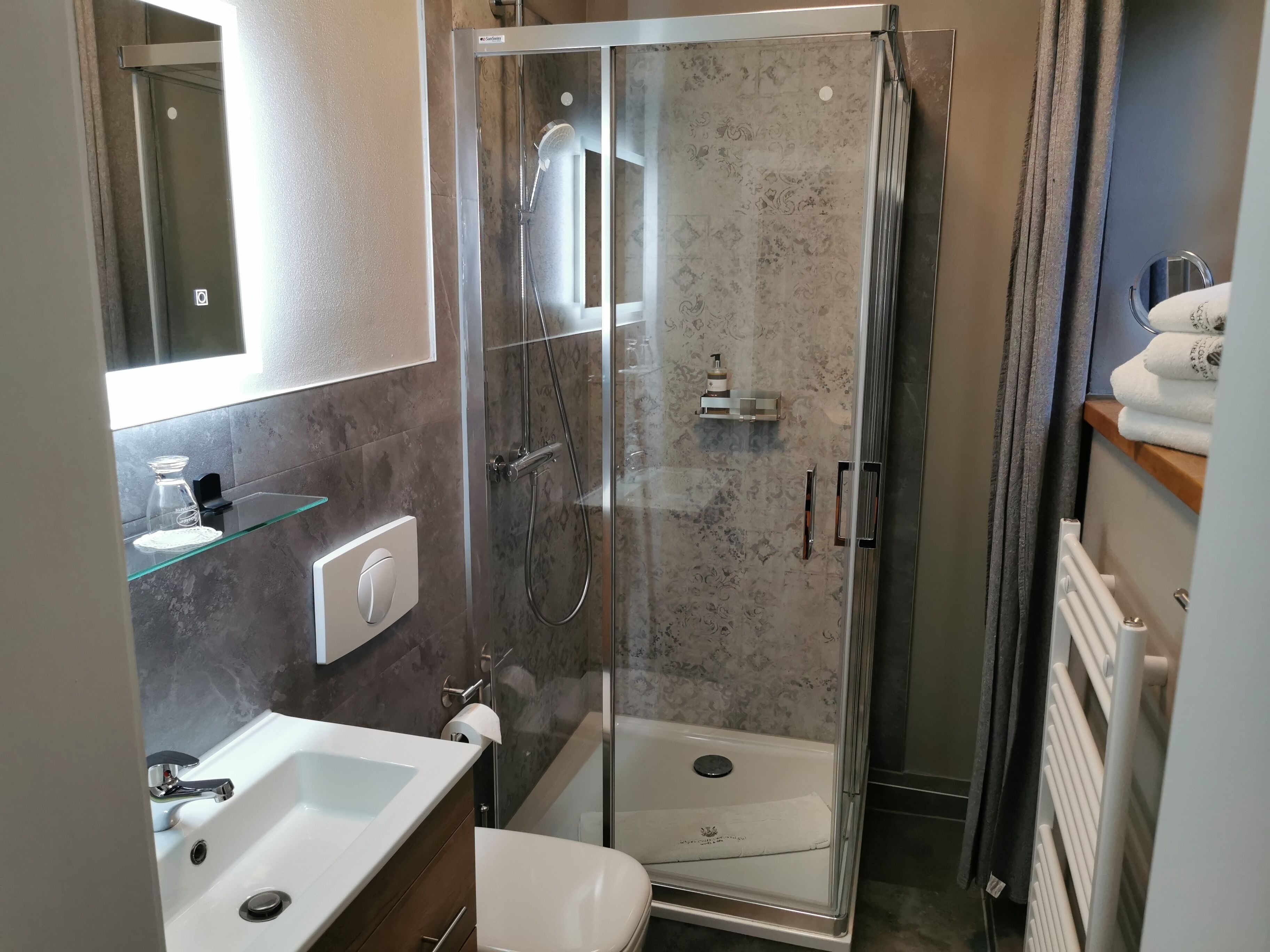 Ein modernes Badezimmer mit einer ein Glasabtrennung versehenen Dusche, einem weißen Waschbecken und einer Toilette.