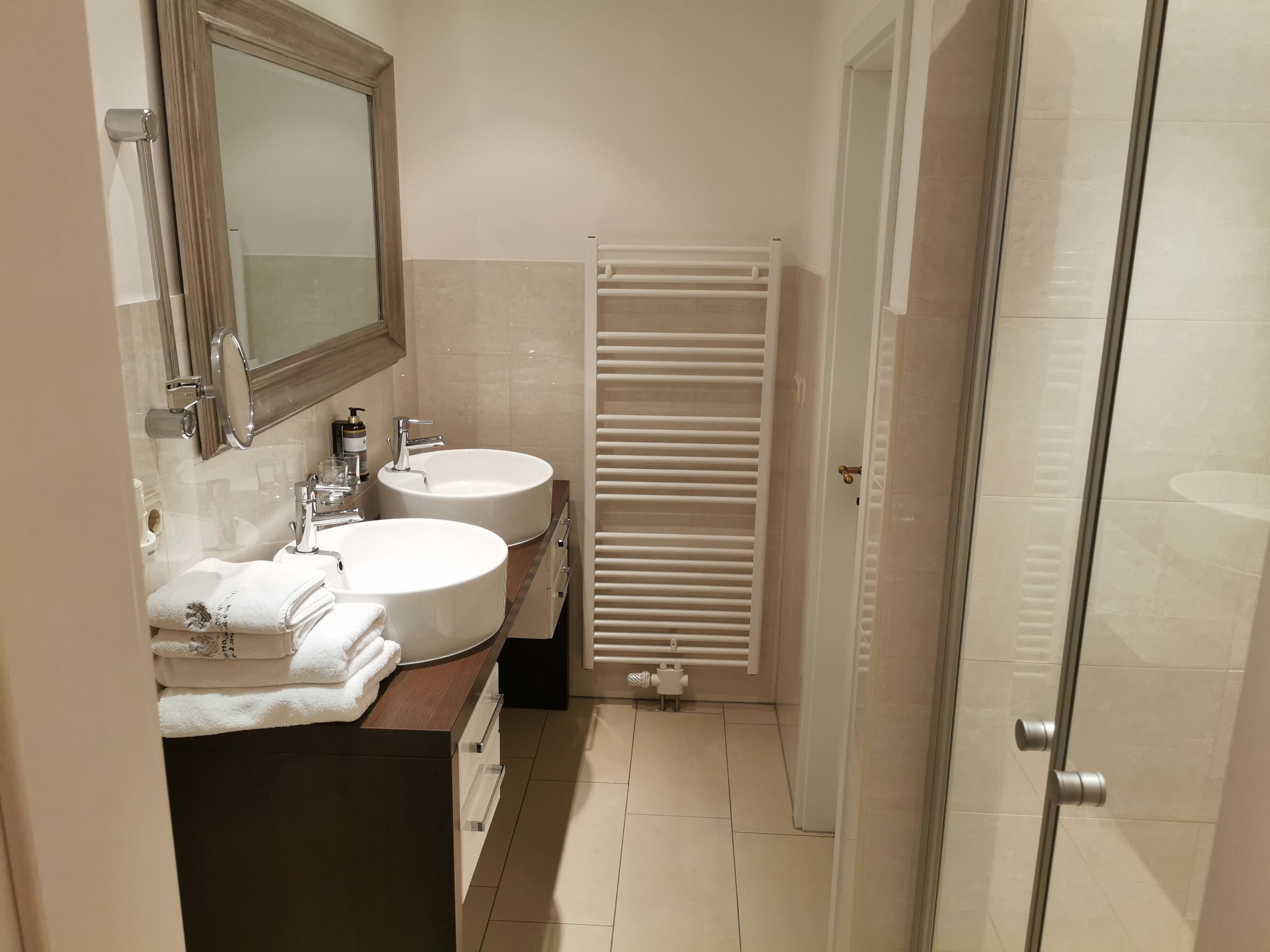 A bathroom with two sinks, a mirror, a towel rack, and a radiator.