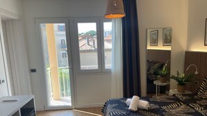 Een slaapkamer met een bed, een bureau, een raam en een balkon.