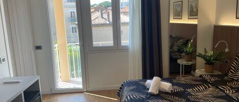 Un dormitorio con cama, escritorio, ventana y balcón.