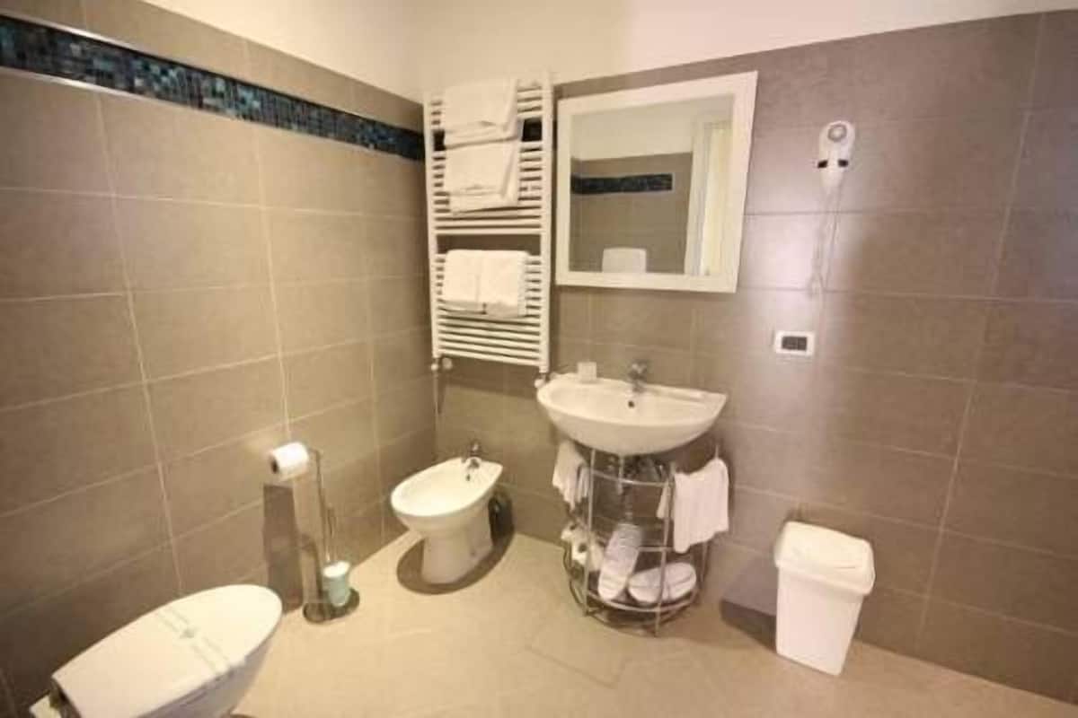 Une salle de bain comprenant des toilettes, un bidet, un lavabo et un porte-serviettes.