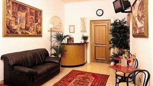 A living room with a leather sofa, a coffee table, a dining table with chairs, a TV mounted on the wall, and a door. - Soggiorno Comfort (Rome)