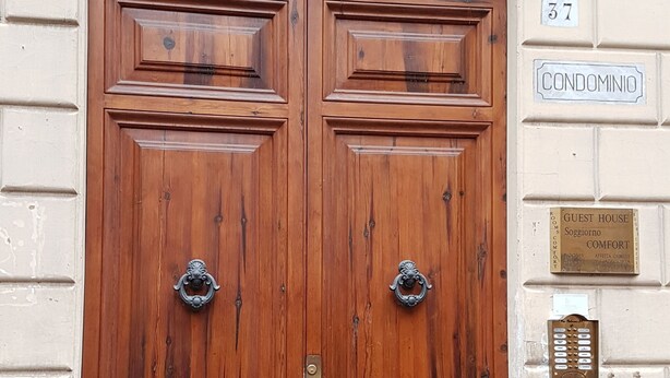 A double wooden door with a metal decorative arch above it, a brass plaque with the number 37, and a sign indicating a guest house named "Soggiorno Comfort". - Soggiorno Comfort (Rome)