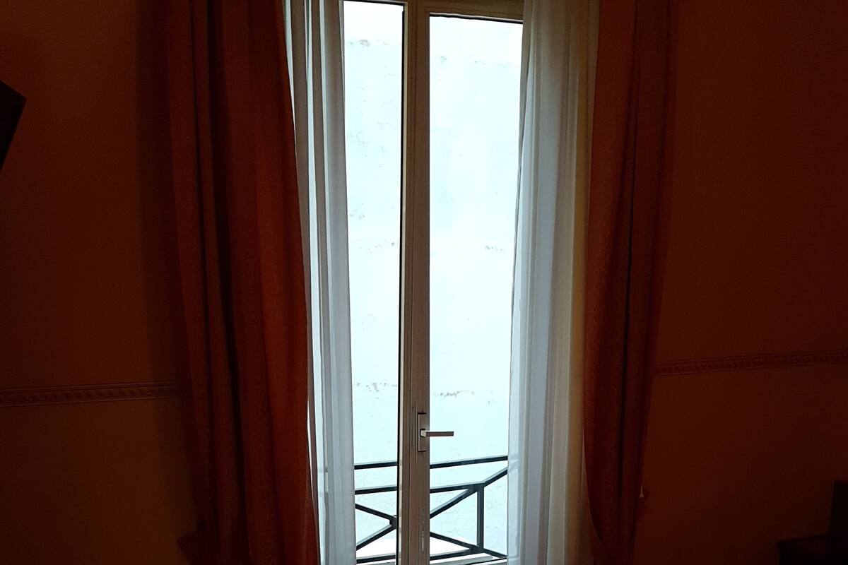 Een hotelkamer met een bed, een stoel, een tafel en een raam met gordijnen.