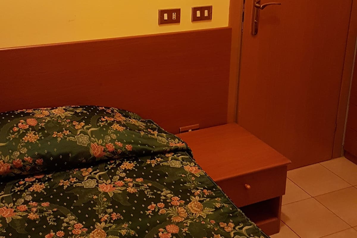 Een kamer met een bed, een houten deur en een wandlamp.