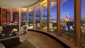 A modern hotel room with a curved glass wall offering a city view at dusk. - Royal International Hotel (Shanghai)