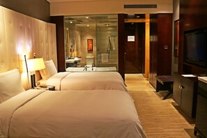 A hotel room with two beds, a large mirror, a TV, and a bathroom with a shower and toilet. - Royal International Hotel (Shanghai)