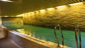 An indoor swimming pool with a stone wall and metal handrails. - Royal International Hotel (Shanghai)