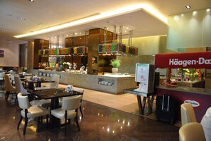 A modern hotel lobby with a central counter, seating area, and a visible sign for Häagen-Dazs. - Royal International Hotel (Shanghai)