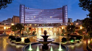A hotel with a central fountain, a curved glass facade, and a well-lit entrance. - Royal International Hotel (Shanghai)