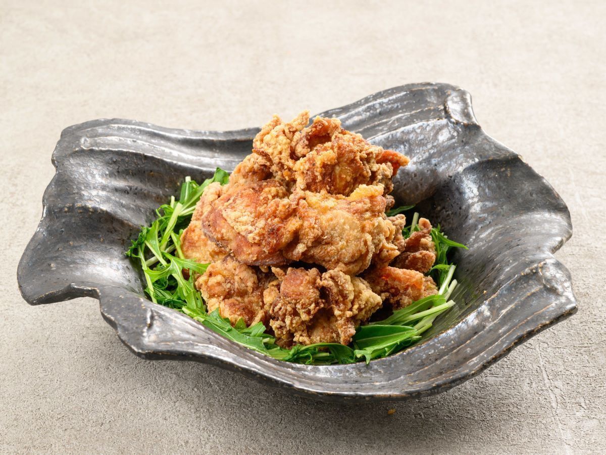 A stack of fried chicken pieces on a decorative plate with green leaves.
