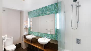A modern bathroom with two sinks, a shower, and a tiled backsplash.