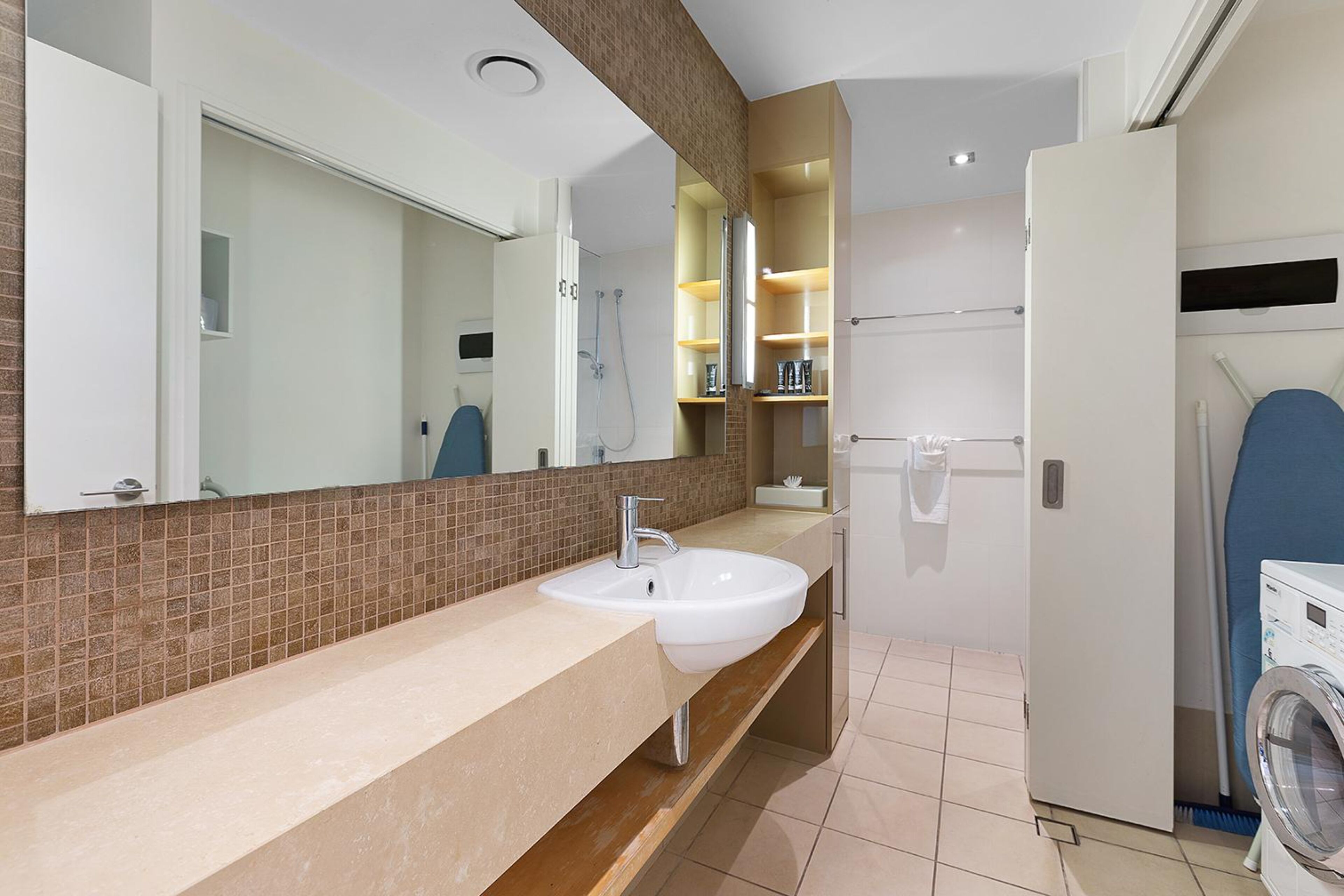A modern bathroom with a large sink, mirror, and a built-in shower.