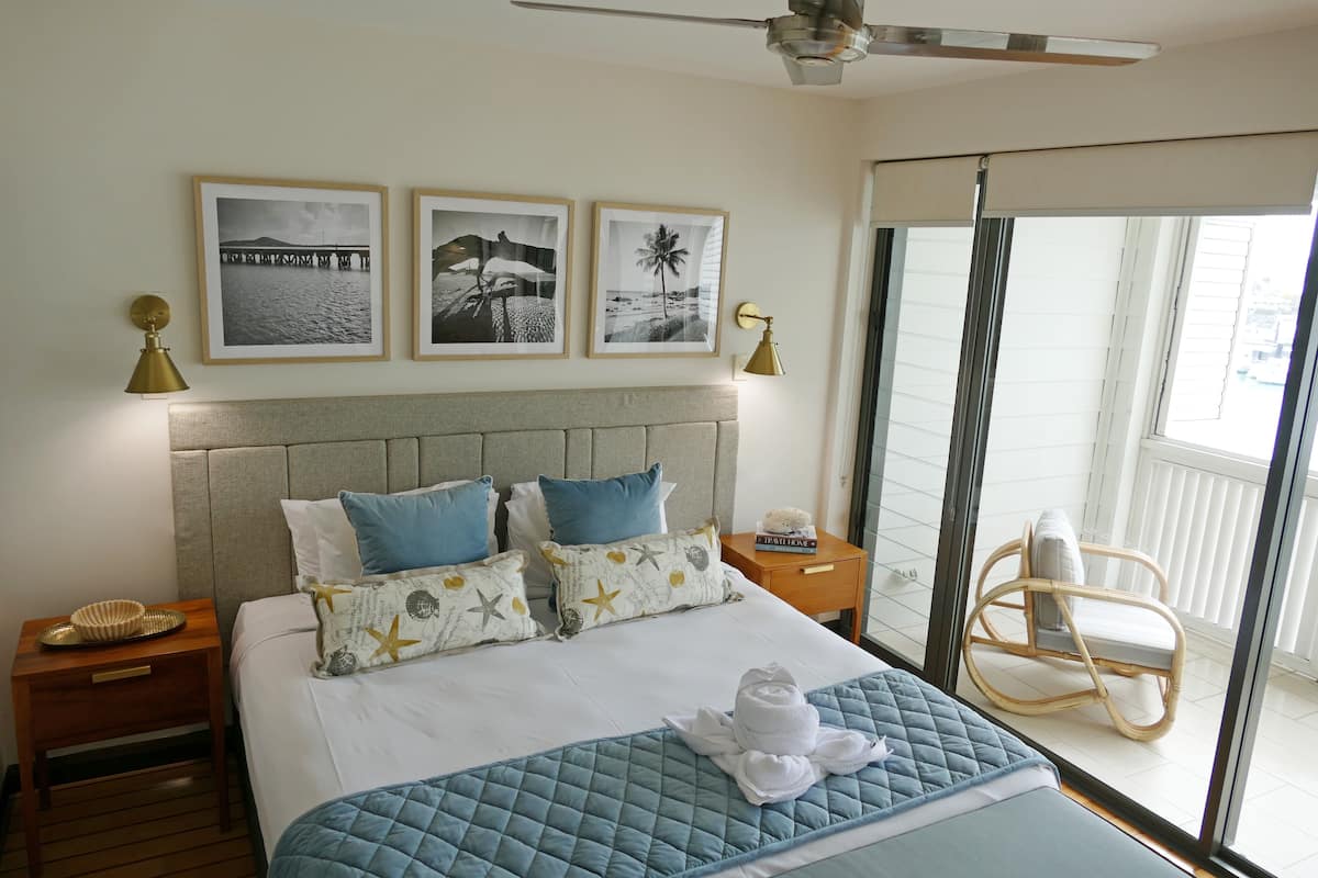 Ein Hotelzimmer mit Bett, Nachttisch, Stuhl und einem Balkon mit Blick.
