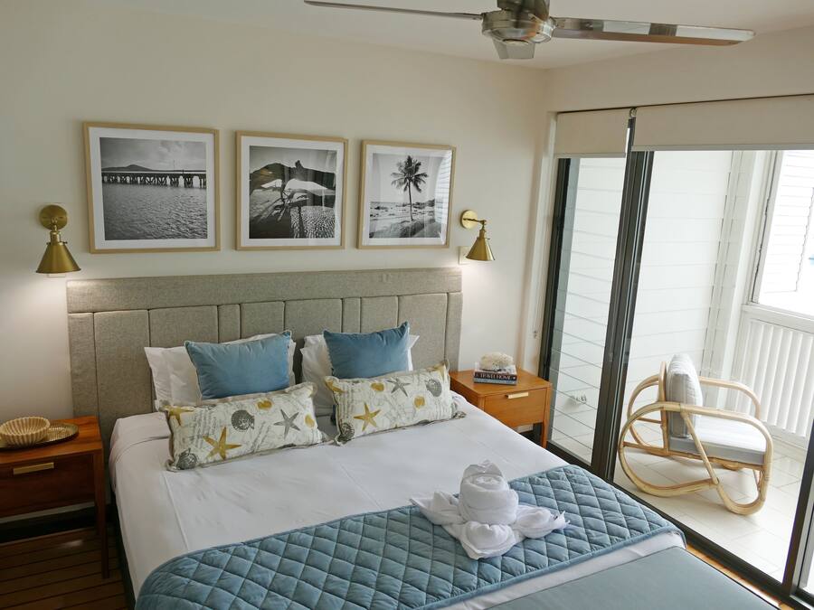 Ein Hotelzimmer mit Bett, Nachttisch, Stuhl und einem Balkon mit Blick.