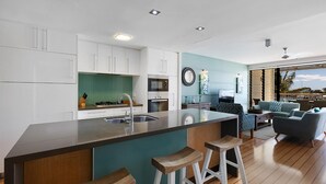 A modern kitchen with a central island, bar stools, and a dining area with a sofa and chairs.