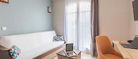 Una habitación de hotel moderna con una cama, un escritorio con una computadora portátil, una silla y una pequeña mesa con un juego de mesa.