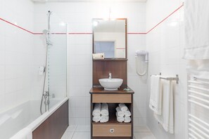 A modern bathroom with a bathtub, a sink, a mirror, and a towel rack. - APPART'City Confort Agen  Centre (Agen)