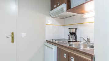 A compact kitchen with a built-in dishwasher, a coffee maker, and a stainless steel sink.