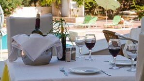 Une table dressée pour un repas en plein air, avec une bouteille de vin, des verres et des salières et poivrières.