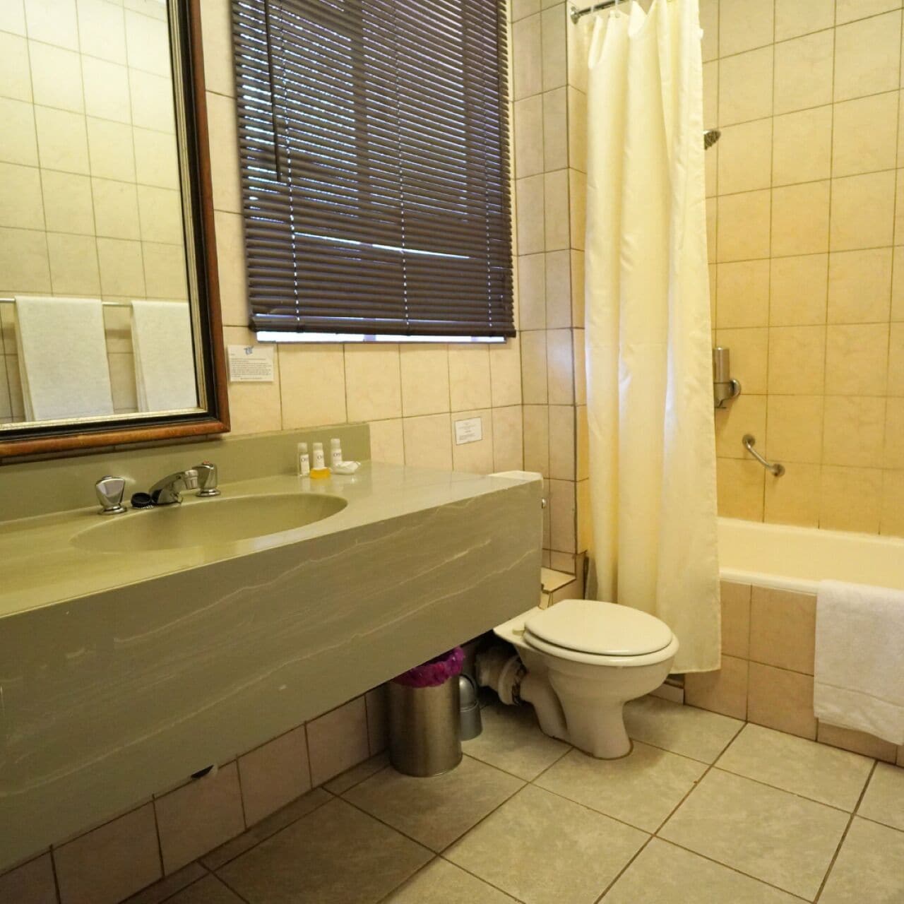 Een badkamer met een wastafel, spiegel, toilet en bad.