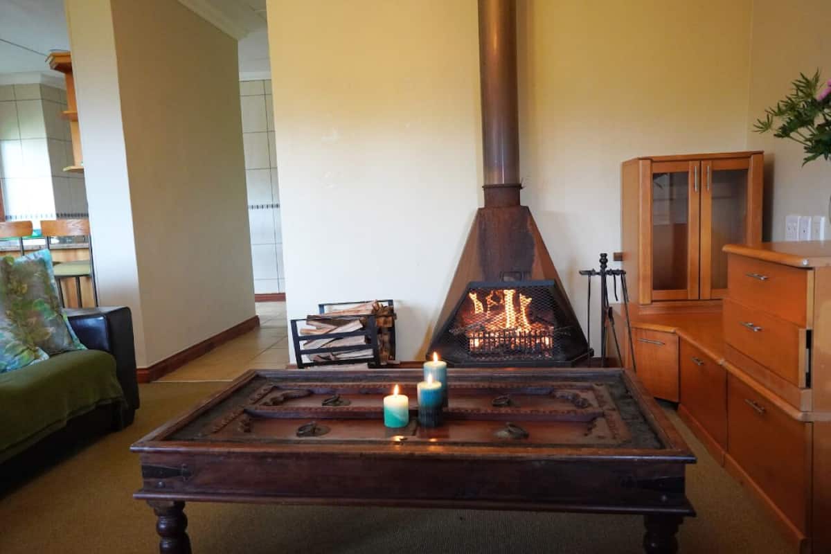 A cozy living room with a fireplace, a wooden table with candles, and a green sofa.