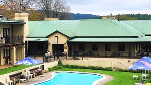 A pool area with a curved pool, outdoor seating, and a building with a green roof.